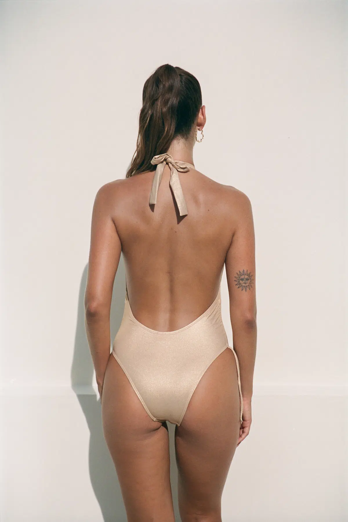 Seen from behind, the golden Tia offers a magnificent open back and classic cut to the buttocks.